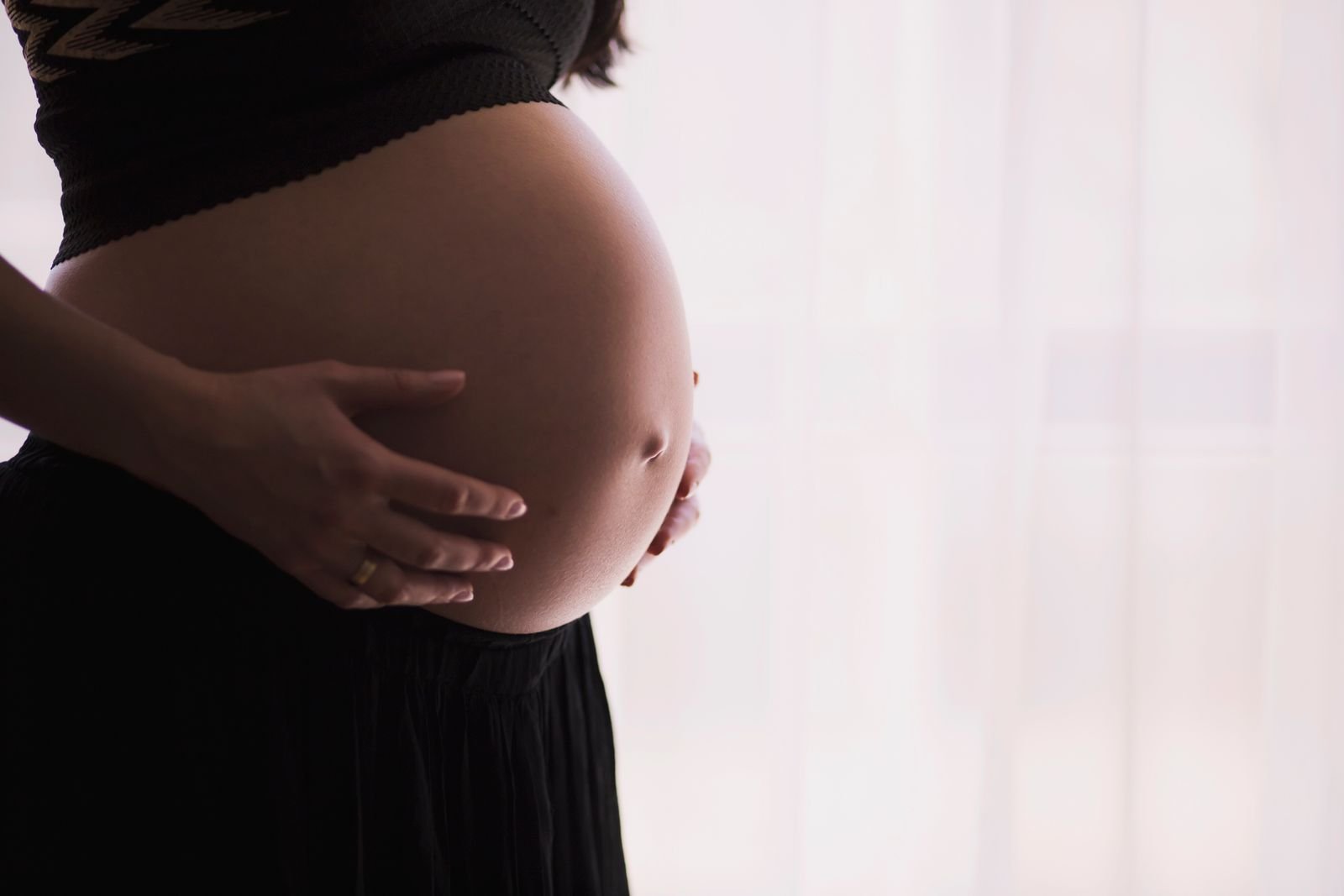 Pregnant client gently holding her belly