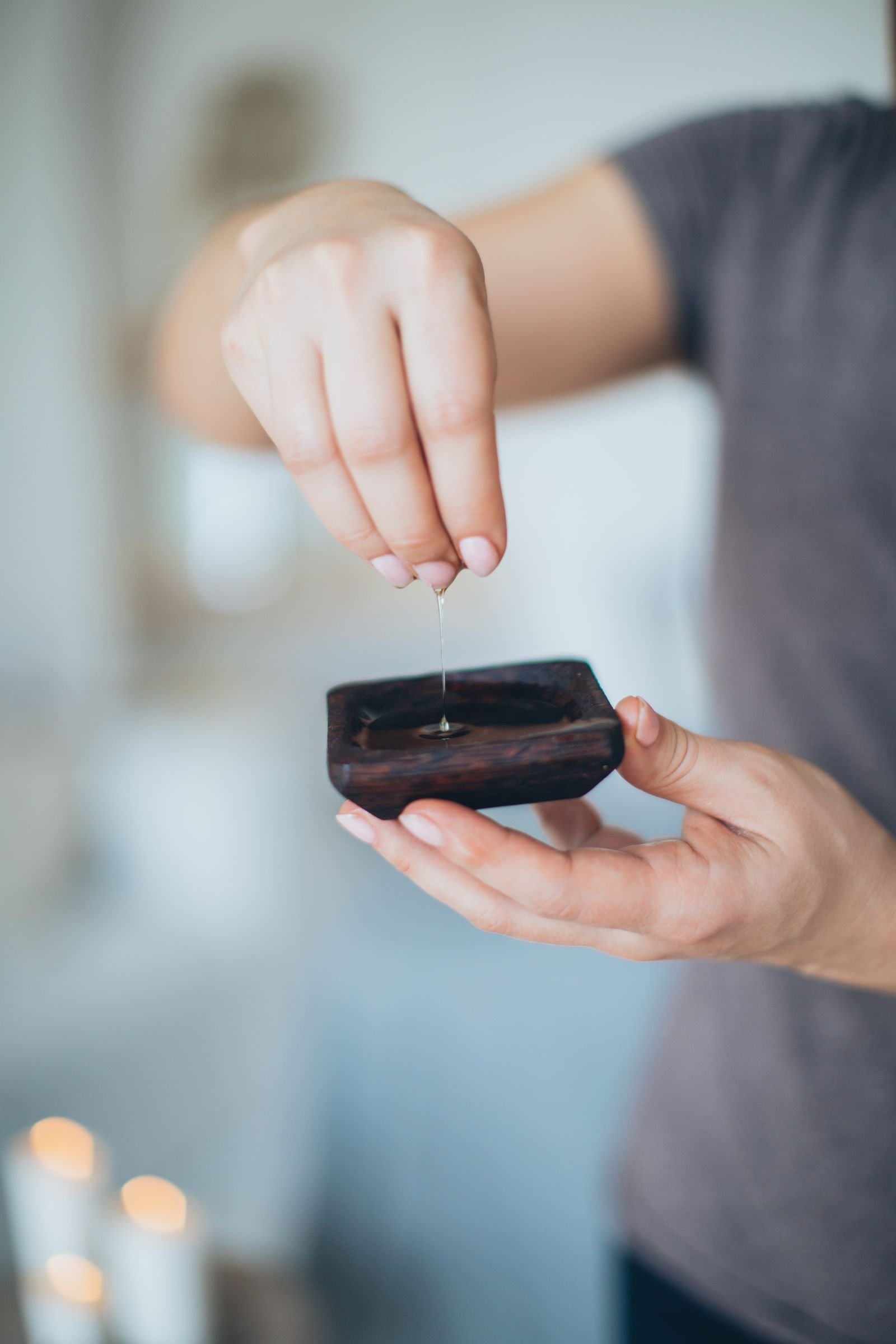 Massage oil dripping into a hand, warm glowing light