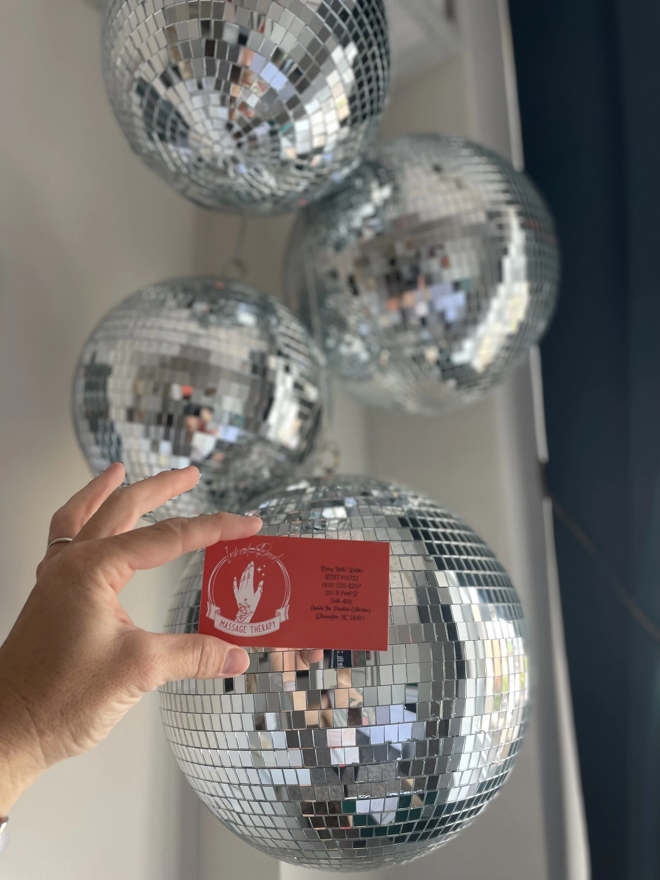 Inked Red business card held against studio disco balls